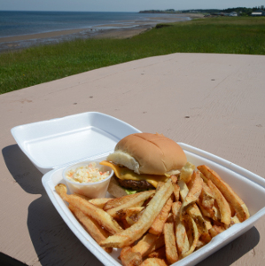 a burger platter on a bench overlooing the beach