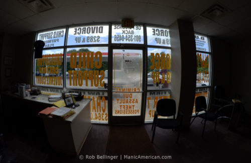 Interior view of a law office within a gas station, looking through windows covered with advertisements for divorce and child support work